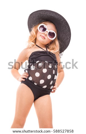 Isolated on white, cute pretty caucasian blonde girl in black swimwear, white sunglasses and big black hat stand, hands on waist, look at camera, turned head
Vertical picture