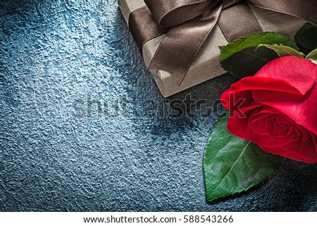 Gift box with brown bow red rose on black background holidays concept.