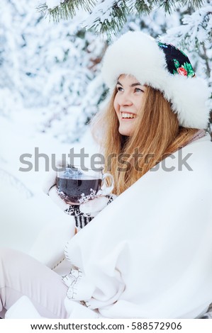 Beautiful girl with a cup of tea in his hands in the winter forest. Close-up