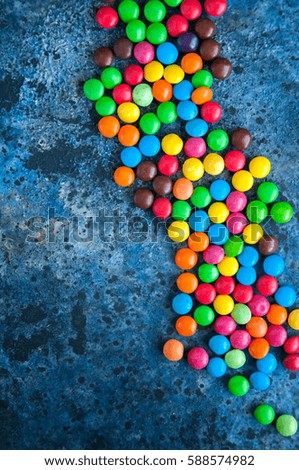 Colorful round candies scattered over blue background. Selective focus.
