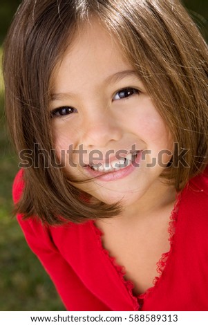 Happy Hispanic little girl smiling outside at the park.
