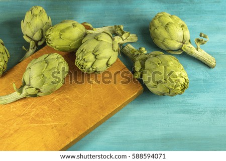 A photo of artichokes on a vibrant turquoise texture with a place for text