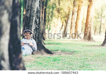 free happy cute girl enjoying. A beautiful kids hipster girl listening to music on headphones in the park.