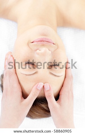 Smiling young woman enjoying a facial massage in a health spa