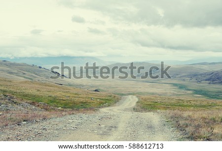 Extreme rocky road path down to a mountain valley from the pass in cloudy dark weather with rain and fog Plateau Ukok Altai Siberia Russia
