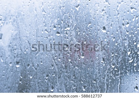 Glass with condensation, natural water drops on glass, high humidity, large drops of water flow down the window, cold tone