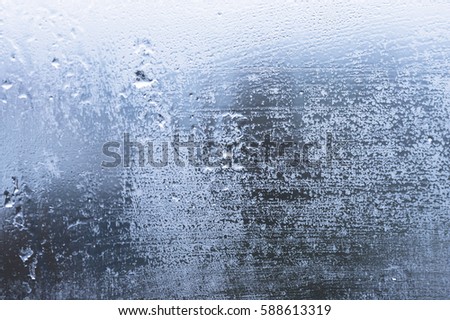 Glass with condensation, natural water drops on glass, high humidity, large drops of water flow down the window, cold tone