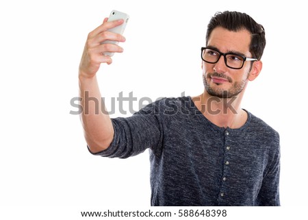 Studio shot of young handsome man taking selfie picture with mobile phone while wearing eyeglasses