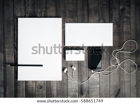 Photo of blank stationery set. Blank corporate identity template on vintage wooden table background. Blank letterhead, business cards, envelope, smartphone, headphones and pencil. Top view.