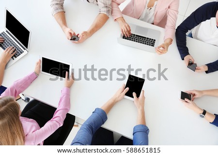 People sitting at table with different gadgets