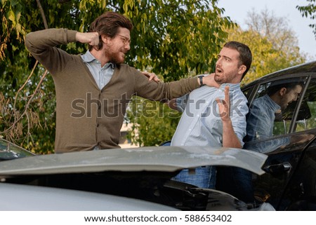 Two men arguing after a car accident on the road Royalty-Free Stock Photo #588653402