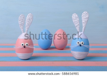 Colorful Easter bunnies and eggs on varicolored wooden background