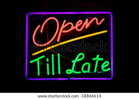Red, green, purple and yellow neon sign of the words 'open till late' on a black background.