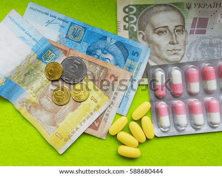 Ukrainian hryvnia in different banknotes and pills on green background. Expensive medicine.