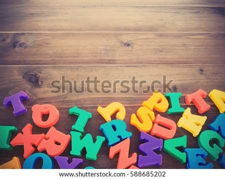 colorful plastic alphabets on wooden table background, vintage filter effect.