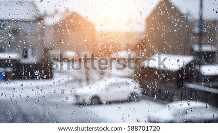 raindrops on glass window looking onto a street in winter     