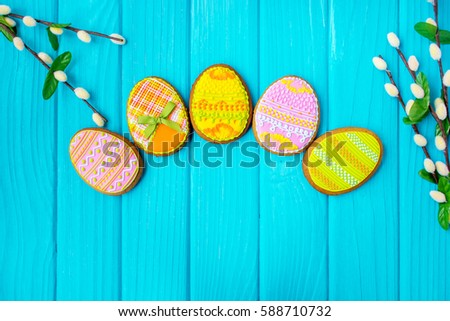 Homemade cookies with icing in the shape of an egg for Easter. Delicious Easter cookies on a blue background. Colored glaze. Cookies for spring mood. Colored eggs on a blue background.