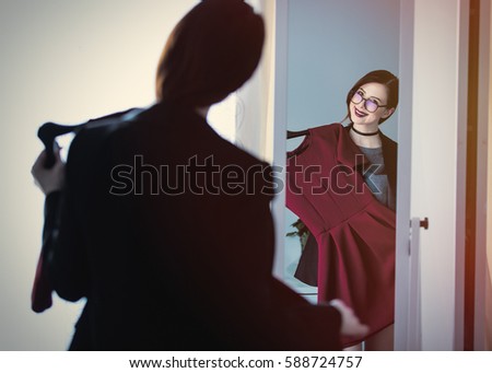 beautiful young woman standing in front of mirror, choosing what to wear and looking at her reflection