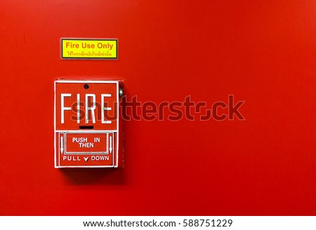 Red fire alarm on the red wall with instruction in Thai and English
