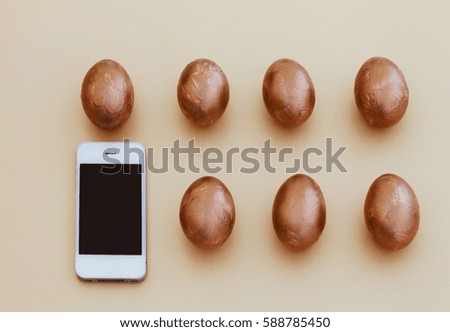Two rows of golden Easter eggs and smartphone