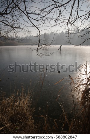 man ice skating on wonderful iced frozen lake in cold winter scenery landscape with backlighting, ljubljana, slovenia