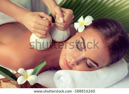 Body care. Spa body massage treatment with hot  herbal ball for deep relaxation . Woman having massage in the spa salon  Royalty-Free Stock Photo #588816260