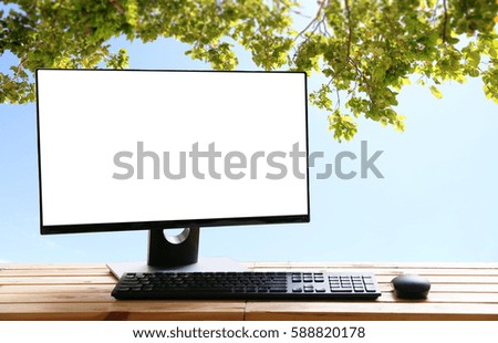 Computer monitor Business and green leaves on wooden table background sky.copy space.concept of time relax.