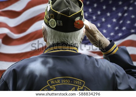 Veteran Saluting  in Front of US Flag Royalty-Free Stock Photo #588834296