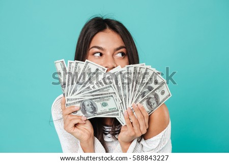 Image of pretty happy young woman posing over blue background holding money.