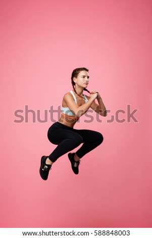 Sideview of pretty woman jumping high while hard training Royalty-Free Stock Photo #588848003