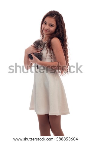 Lovely girl brunette with long hair in a white dress with a small gray kitten on a white background in studio