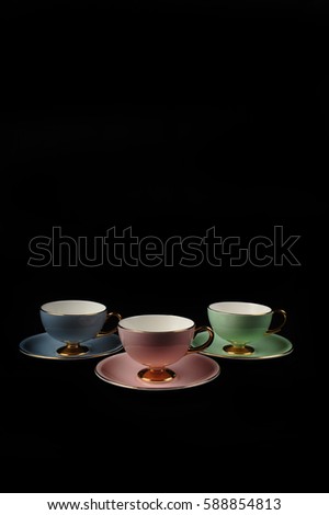 Three vintage mocha cups with gold decor against black background.  Pastel pink, green and blue cups with coffee. Frontal view.  Copy space in upper and lower part of vertical photo.