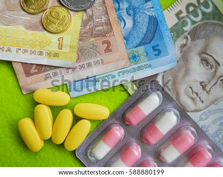 Close up photo of ukrainian hryvnia in different banknotes and pills on green background. Expensive medicine. High prices for drugs in Ukraine.