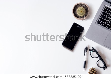 White office desk table with laptop, pinecones, smartphone, and cactus. Top view with copy space, flat lay.