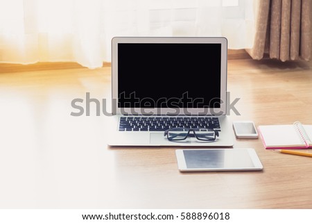 Laptop and stationery items on the wooden floor with light effect