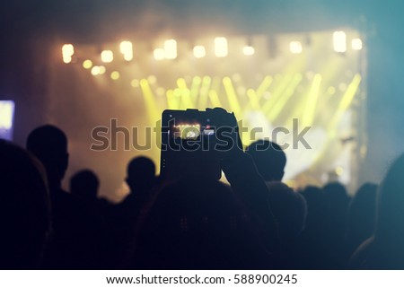 Silhouette of hands using camera phone to take pictures and videos at pop concert, festival.Retro styled photo.