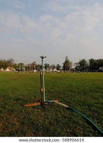 Rugby football field in green grasses and sprinkler water
