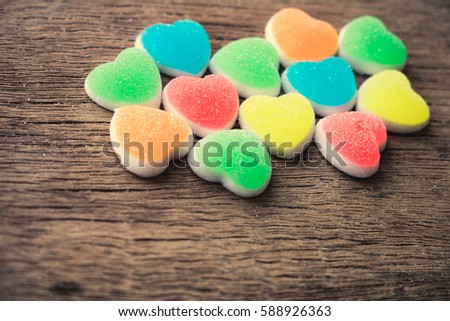 Colorful candy hearts on wooden background.