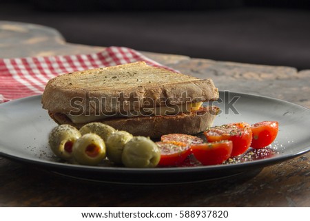 Closeup picture of delicious feta cheese sandwich with green olive, small tomatoes on a plate.