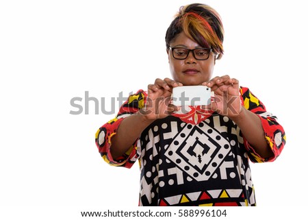 Studio shot of fat black African woman taking picture with mobile phone