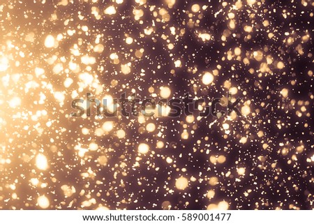 Golden abstract sparkles or glitter lights. Festive gold background. Defocused circles bokeh or particles. Template for design Royalty-Free Stock Photo #589001477