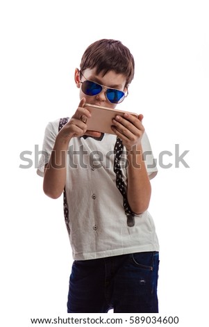 Boy brunette in a white shirt with suspenders and sunglasses playing on the phone on a white background