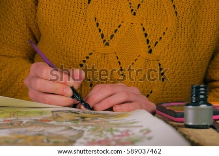 female artist drawing/painting a picture of lynx with ink and watercolor under the artificial light