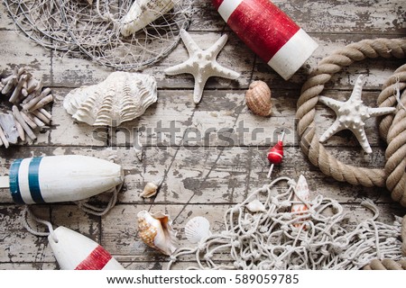 Stylized sea theme flatlay with shells, sea star, rope, sailor and ship accessories top view. Fishing items from above with copy space for text. Vintage wooden background. Creativity concept