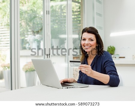 Mature woman using laptop with credit card