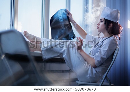 Brunette sassy female nurse in uniform smoking a cigarette and looking at x-ray picture of backbone