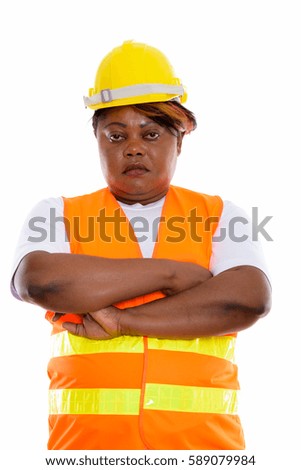 Studio shot of fat black African woman construction worker with arms crossed