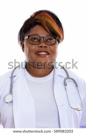 Face of happy fat black African woman doctor smiling and thinking while wearing eyeglasses