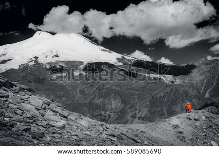 A lone tourist among the big mountains. Black and white photo.