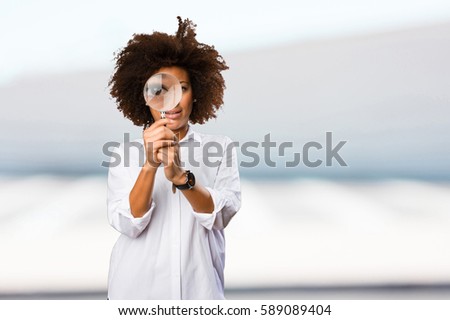 young black woman looking through the magnifying glass